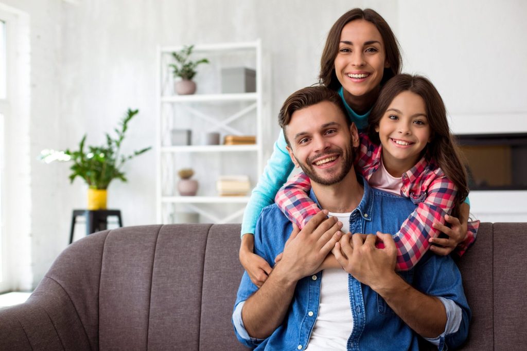 cerrar-foto-madre-padre-e-hija-posando-juntos-foto-conjunta-su-elegante-sala-estar-abrazandose-radiantes-sonrisas-scaled