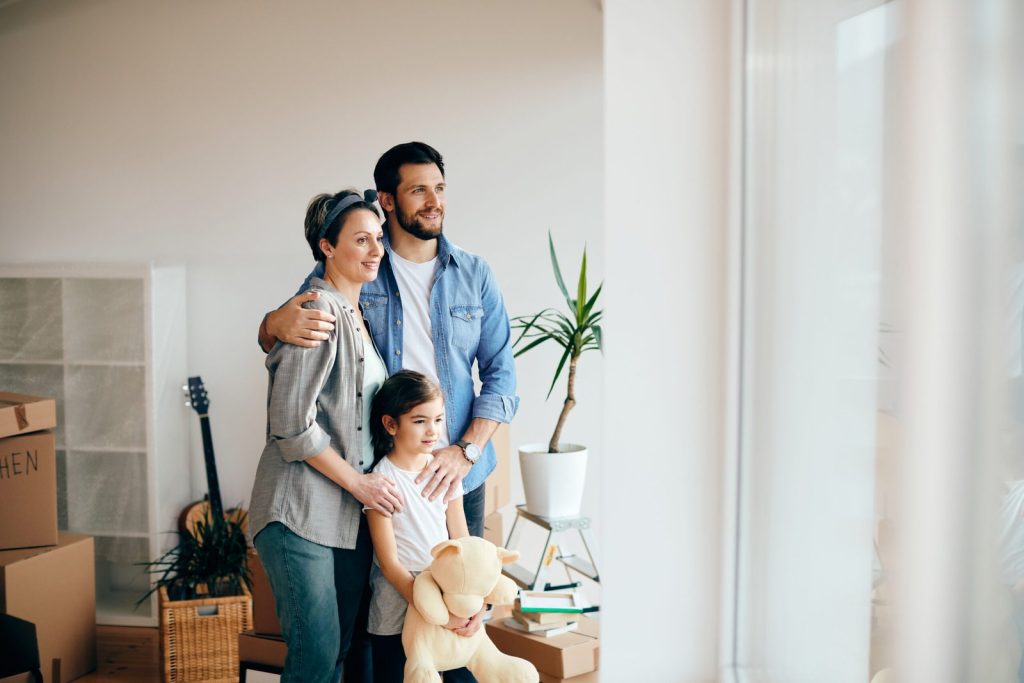 happy-family-looking-through-the-window-while-moving-into-new-home-scaled