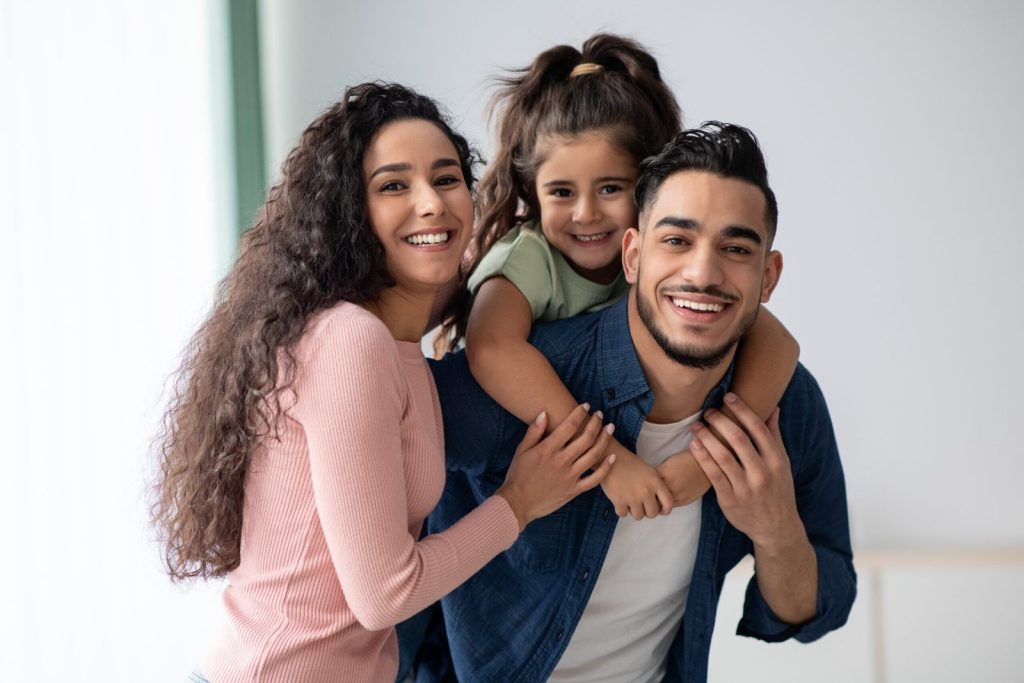 portraif-happy-young-arabic-family-three-with-little-daughter-middle-eastern-mom-dad-kid-having-fun-while-posing-home-parents-enjoying-spending-time-with-their-child-free-space-1-scaled