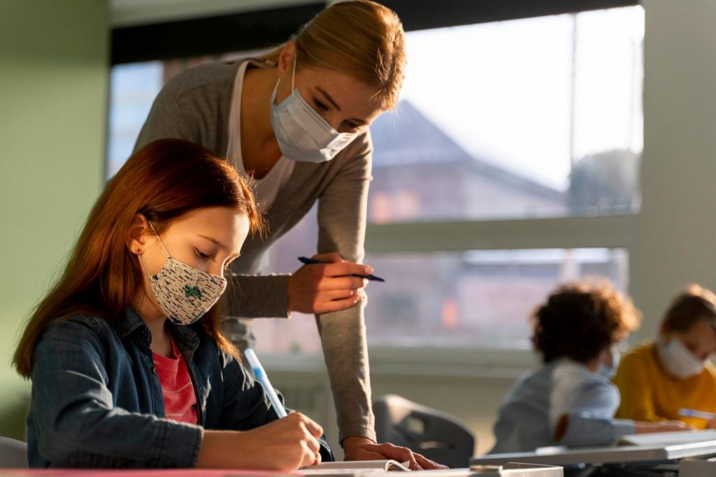 side-view-of-children-learning-in-school-with-teacher-during-the-pandemic-scaled