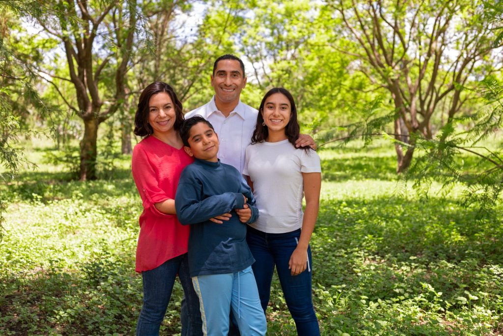 vista-frontal-familia-sonriente-afuera-scaled