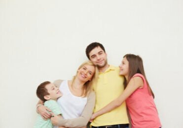 Portrait of affectionate family of four posing over white background
